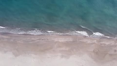 Top View of Breaking Waves on a Sandy Beach