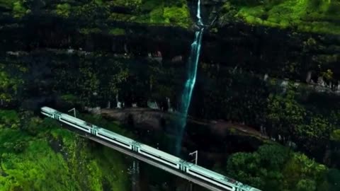 Watch: Train Passing Over Bridge Next to Waterfall Surrounded by Mountains! 🚂🌊🏞️