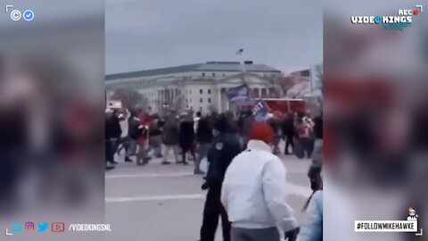 Police officer waves to Trump Supporters to join the masses entering the Capitol.