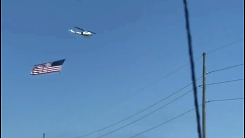 HELICOPTER FLYING ENORMOUS AMERICAN FLAG SUPPORTING THE PEOPLES CONVOY