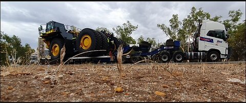 Volvo semi with lowboy low loader transporting oversize load Komatsu mining haul truck