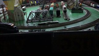 Three trains running around the layout at night with lights on the HO deck