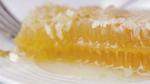 Dessert - honeycomb on a plate clouse-up on the background of the blurred girl having Breakfast in