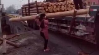 Une femme minuscule déplace un immense tronc d'arbre