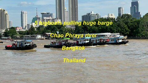 5 tugboats pulling huge barge at Chao Phraya river in Bangkok Thailand