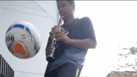 Man does keepie-uppies while playing clarinet