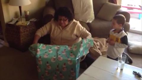 Christmas Prank: A woman unwraps a box indoors and her son jumps out of it