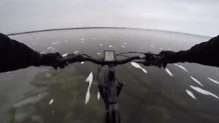 Un cycliste traverse un lac gelé et transparent