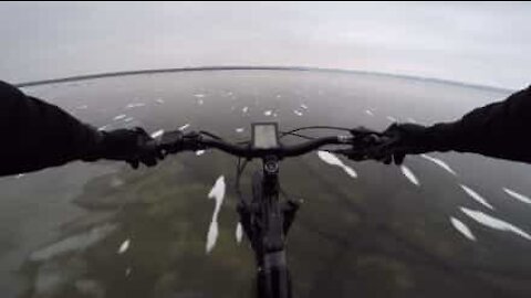 Un cycliste traverse un lac gelé et transparent