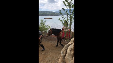 riding a horse by Lugu lake