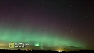 Bright green auroras stream upwards into the night sky