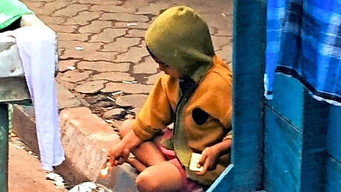 Young Indian boy tries to set trash on fire with matches