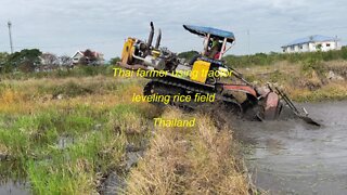 Thai farmer using tractor leveling rice field in Thailand