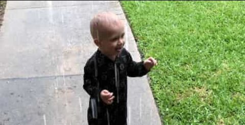 Boy plays in rain for the first time