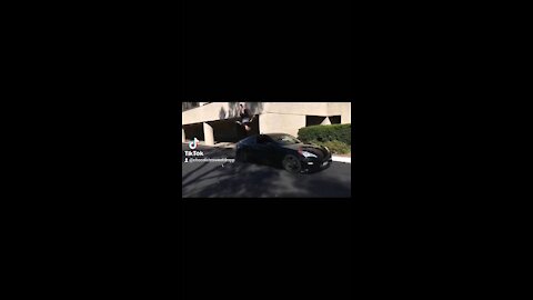 A guy does a flip on a wall over a car