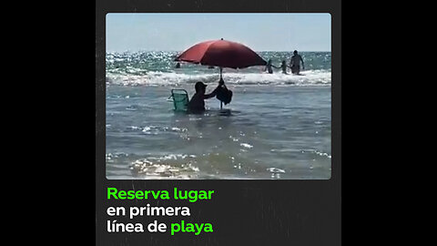 Un bañista español se mete en el agua con silla y parasol