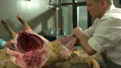 Butcher cutting pork carcass at the meat Butcher cutting pork carcass at the meat manufacturing Ind