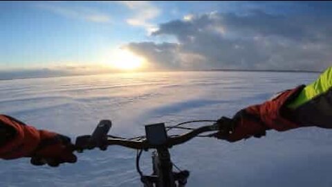 Il roule en VTT sur un lac gelé au coucher du soleil