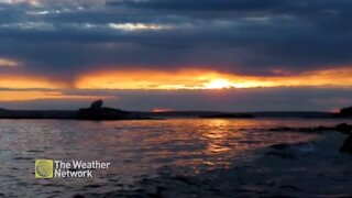 Sinking sun glows between the clouds creating golden waves