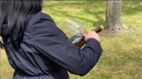 Woman uses glass to open bottle of champagne