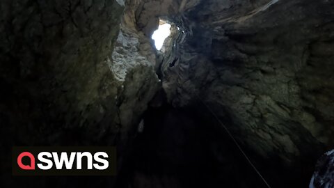 Claustrophobic footage shows group of thrill-seeking men abseiling down crystal ice cave