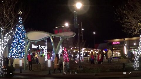 Christmas Music 1 hour In front of a festive setting with people shopping and ice skating going on.