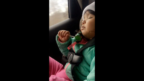 Sleepy baby licks her lollypop to sleep