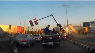 A truck slides across street and crashes into traffic light