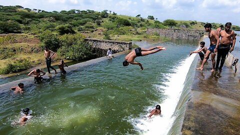 The children are jumping and swimming in the river.