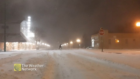 Lonely figure trudges down snow-covered road