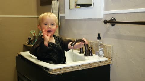 Baby boy playing in bathroom sink.