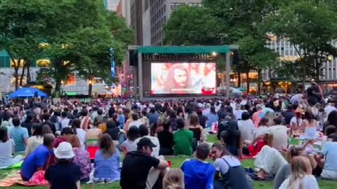 An open-air movie in a park in new york is crowded with people.