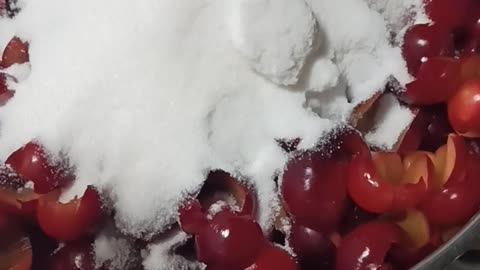 Adding sugar to cherry plums for jam