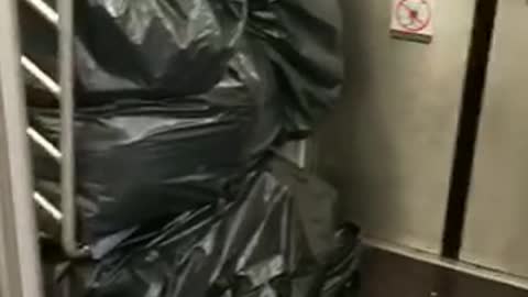 Black trash piled up man in cardboard boxes