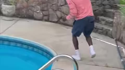 The dog tries to bite him but he jumps into the pool