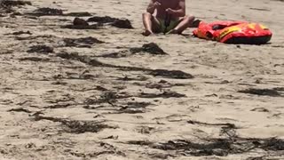 Man on beach next to orange raft has shake weight