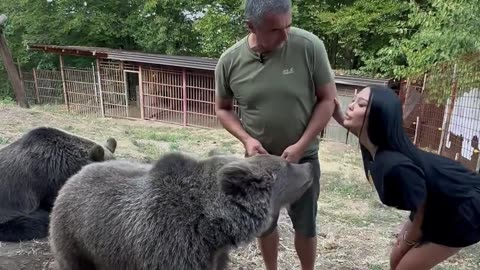 A girl feeds a bear from her mouth