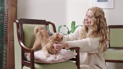 a woman is brushing her cat in her house