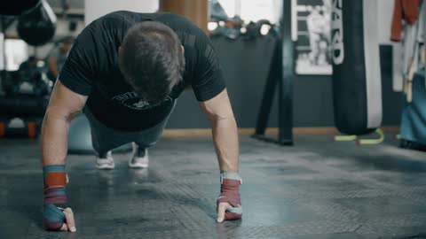 A man plays cardio and push-ups in the boxing gym