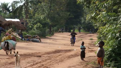 Rural Dirt Road In Africa With Children Dogs And Bicycles