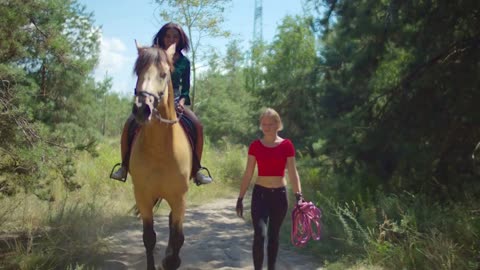 Joyful pretty black female riding on horseback in summer forest