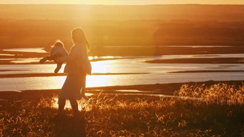 Woman and her baby spinning at sunset