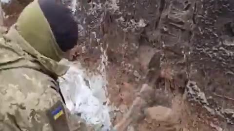 Ukrainian soldier resorts to using an axe to "dig" a trench because the ground is frozen