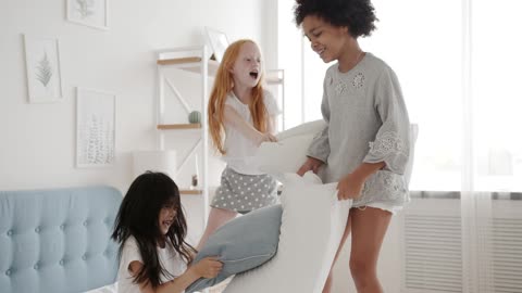 Young Playful Girls Fighting with Pillows