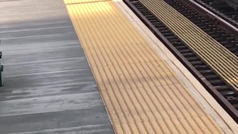 Man black hat standing on yellow line incoming train