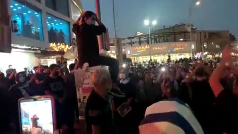 Scenes in Iran tonight, a woman sits on top of utility box and cuts her hair in the main square