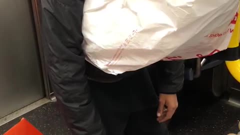 Man sleeping on white bag standing up subway