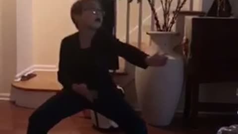 Little boy in all black does dance falls next to coffee table