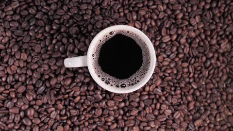 Cup of coffee on top of coffee beans