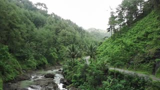 An Aerial Footage of a Winding Road beside Mountain Forests